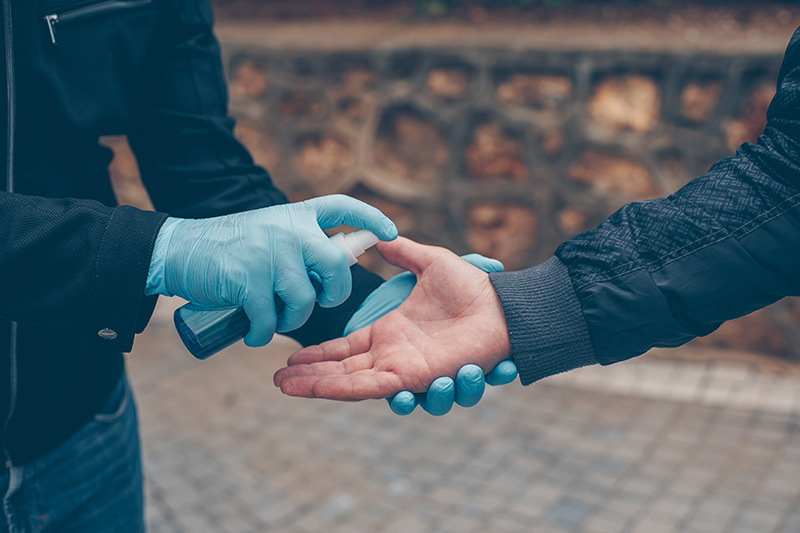  Una persona con guantes azules rociando desinfectante de manos