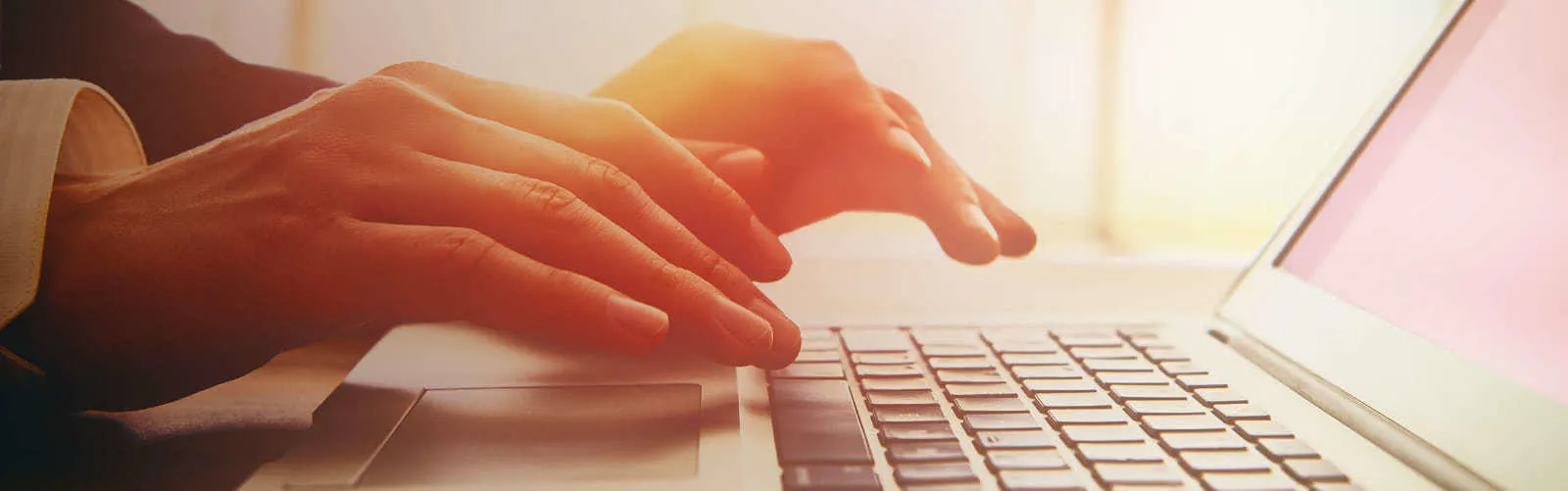Hands typing on a laptop keyboard