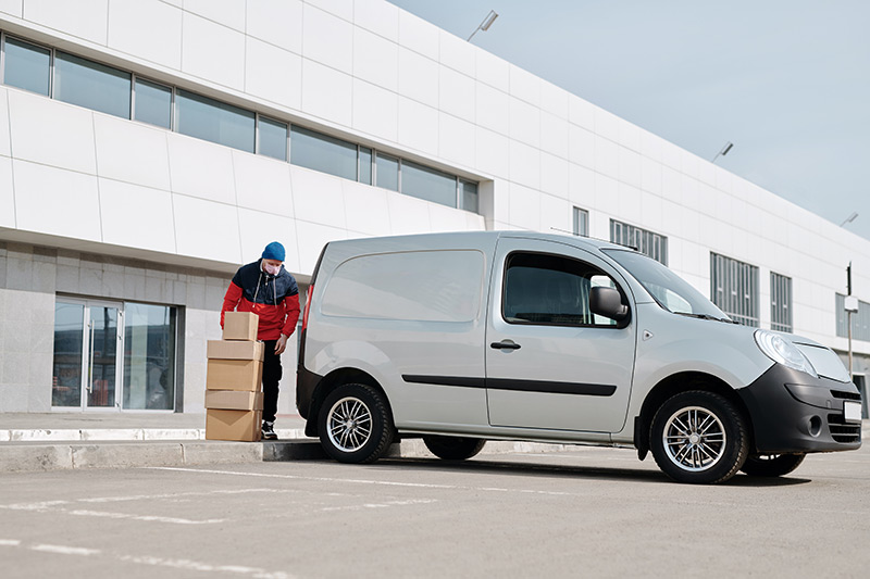 Person loading cardboard boxes into silver van