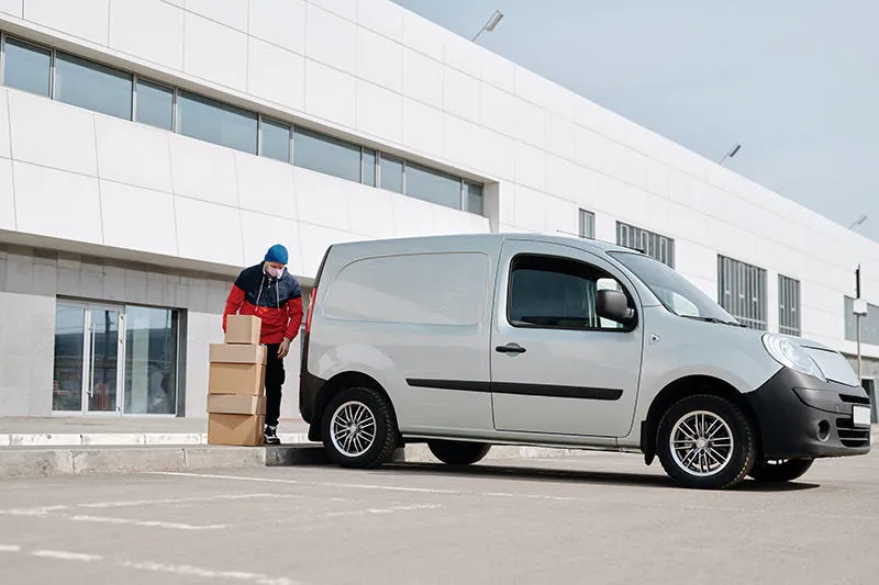 Person loading cardboard boxes into silver van