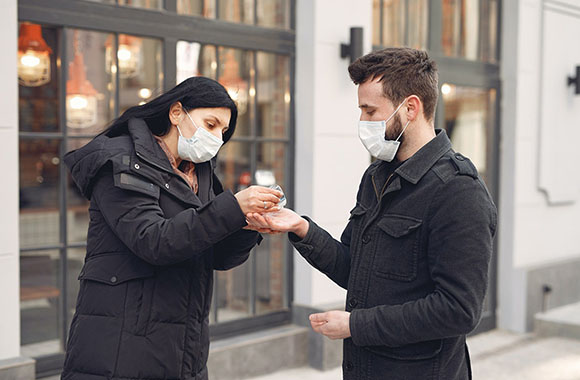  Dos personas con mascarillas con desinfectante para manos
