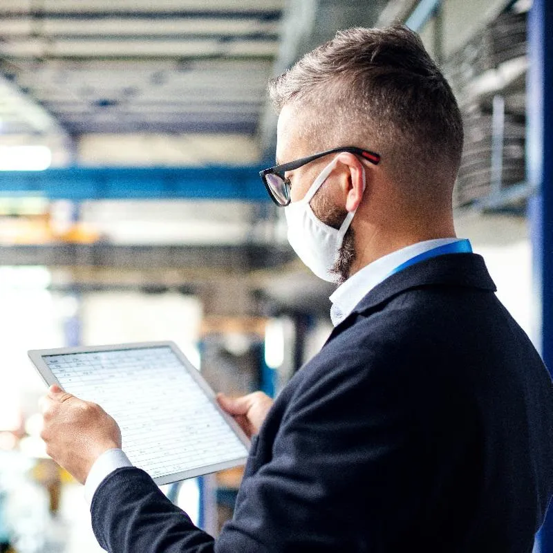 Man looking at tablet, wearing a mask and glasses