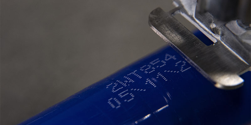 파란색 기질의 소재에 적용된 하얀색 연속식 잉크젯 마킹 코드